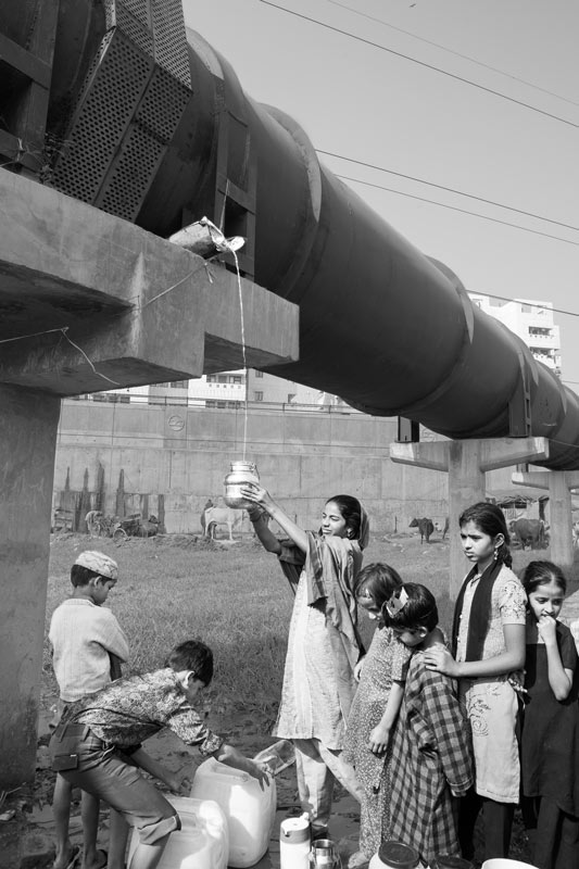 Human Right to Water in Delhi - Children residing in an unauthorized colony in Delhi collecting potable water as a trickle from a city mainline leakage